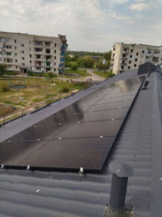 Solar panel in front of a damaged residential building